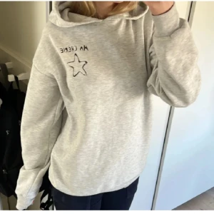 Grå hoodie med text och stjärna - LÅNADE BILDER!! Snygg grå hoodie med texten 'MA CHÉRIE' och en stjärna tryckt på både fram- och baksidan. Perfekt för en avslappnad stil. Hoodien har en klassisk passform med långa ärmar och en bekväm huva.