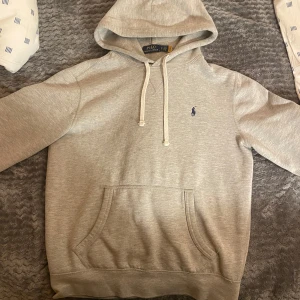 Grå hoodie från Ralph Lauren - Säljer en stilren grå hoodie från Ralph lauren. Tröjan är riktigt schysst och funkar till de mesta och är riktigt snygg. Har inte sätt sån tröja här på plick på ett bra tag. Den är i S men funkar lika bra till M. Tröjan har två rosa fläckar som inte syns vid användning 