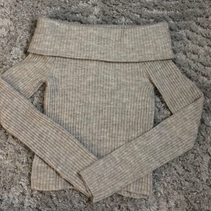 Beige ribbad offshoulder tröja från H&M - Säljer en beige ribbad offshoulder tröja från H&M. Aldrig använd, så den är i nytt skick. Säljer på grund av att den inte kommer till användning.