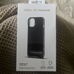 Svart mobilskal Ideal of Sweden - Snyggt och stilrent mobilskal i färgen Mirror Black från Ideal of Sweden. Passar både iPhone 13 och iPhone 14. Skalet är oanvänt, men förpackningen är liite trasig (se bild). 