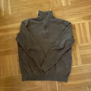 Brun half zip stickad tröja från Zara - Snygg brun stickad tröja från Zara i storlek S. Tröjan har en hög krage med half zip-dragkedja och långa ärmar. Ribbad kant vid hals, ärmslut och nederkant ger en clean look. Perfekt för dig som gillar enkel och stilren design.
