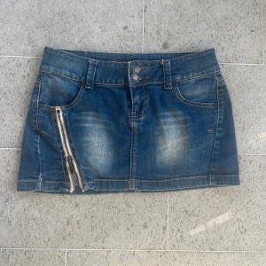 Blå jeanskjol med dragkedja från Fishbone - Snygg blå jeanskjol från Fishbone med cool dragkedjedetalj framtill och klassiska fickor både fram och bak. Kjolen har dubbla knappar i midjan och bälteshällor, perfekt för en chill och trendig look. Midjemått: 37cm. Säljer fler kjolar på mitt konto! Använd gärna köp nu eller kom med prisförslag❤️