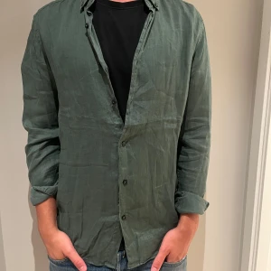 Grön långärmad linneskjorta från Zara - Snygg grön skjorta i linne med klassisk krage och knäppning framtill. Skjortan har lång ärm och en avslappnad passform, perfekt att bära öppen över en t-shirt eller knäppt. Enkel och stilren design som funkar till många outfits. Otroligt bra skick, använd ett fåtal gånger. 