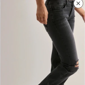 Nelly low waist jeans - Snygga svarta low waist jeans med slitningar vid knäet och coola detaljer på bakfickorna. Jeansen har en tight passform och klassisk femficksdesign. 