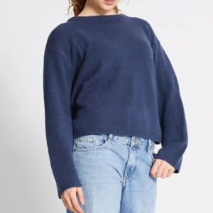 Mörkblå stickad tröja med loose fit - En enkel och stilren mörkblå stickad tröja med loose passform. Tröjan har rund halsringning och långa ärmar, perfekt att matcha med jeans för en chill look. Ribbstickade muddar vid ärmslut och nederkant ger en snygg finish.
