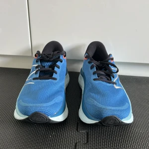 Blå New Balance Fresh Foam sneakers - Snygga blå New Balance Fresh Foam sneakers med svart innersida, svarta skosnören och detaljer i silver och orange. Ovandel i mesh för bra andningsförmåga och en riktigt chunky, ljusblå sula med cool struktur. Perfekta för dig som gillar att träna eller vill ha en sportig look. Dom är bara testade en gång men passade inte. Storlek 41,5