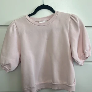 Ljusrosa puffärm tröja Gina Tricot - Supersöt ljusrosa tröja från Gina Tricot med puffiga korta ärmar och rund hals. Mjuk och skön i bomullsmix, perfekt för dig som gillar en chill men ändå trendig look. Ribbad kant vid hals, ärmslut och nederkant. Passar dig som vill ha något gulligt och comfy. priset går att diskuteras