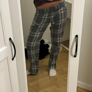 Grönrutiga pyjamasbyxor  - Säljer ett par grön/gråa pyjamasbyxor med vitt rutmönster och snörning i midjan. De har en rak passform och är tillverkade i ett mjukt bomullsliknande material. Perfekta för en chill och avslappnad stil. Storleken är xs men passar mig med S och m