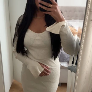 Vit ribbad långärmad klänning - Snygg vit ribbad klänning med lång ärm och lätt utsvängda ärmslut. Klänningen har en figurnära passform och en v-ringad halsringning som ger en modern vibe. Perfekt för dig som gillar stilrena och enkla plagg med en twist. (Står storlek S men tror att det är M) 