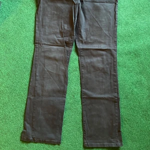 Svarta byxor från Canard Collection - Svarta byxor från Canard Collection i storlek 44. Byxorna har raka ben, dekorativa paljetter på bakfickorna och kontrastsömmar. Materialet känns mjukt och har en lätt stretch. Perfekta för dig som gillar en stilren look med lite extra detaljer.