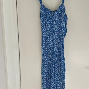 Blommig blå klänning FB Sister - Säljer en blå klänning från FB Sister i storlek M. Klänningen har ett sött blommigt mönster i vitt och ljusblått, smockad rygg och smala axelband med volangdetaljer. Perfekt för sommarens alla tillfällen, superfin och flowy passform.