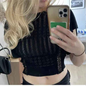 Svart spetstopp med öppen rygg och volanger - Supersnygg svart croppad blus med spetsdetaljer och volanger. Hör av er vid frågor💗