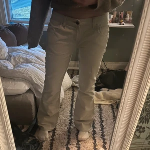 Ljusblå bootcut jeans - Säljer ett par snygga beiga jeans med bootcut-modell. Byxorna har klassisk femficksdesign, bälteshällor och stängs med knapp och dragkedja. Perfekta för dig som gillar en stilren och enkel look.