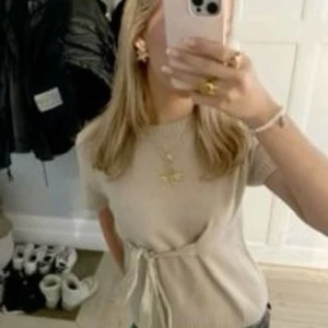 Beige stickad topp med knyt från Zara - Superfin beige stickad topp från Zara med korta ärmar och snygg knytning i midjan. 