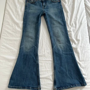 Blå bootcut jeans från Monki 26/32 - Säljer ett par blå bootcut jeans från Monki i storlek 26/32. Normal passform upptill, mitt i mellan hög och låg midjade och utsvängda ben.