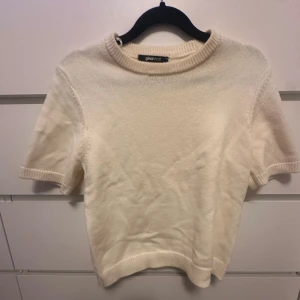Krämvit stickad tröja Gina Tricot - Superfin krämvit stickad tröja från Gina Tricot med korta ärmar och rund hals. Mjuk och skön kvalitet, perfekt att styla med jeans eller kjol. Ribbad kant vid hals, ärmslut och nederkant ger en clean look. Passar dig som gillar enkel och stilren vibe.