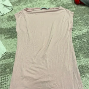 Ljusrosa kortklänning från 157 - Enkel och stilren ljusrosa kortklänning från 157 i mjuk bomull. Klänningen är ärmlös med rund halsringning och har en rak, avslappnad passform. Perfekt för varma dagar eller att styla med accessoarer.