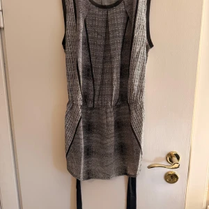 Mönstrad kort topp Calvin Klein XS - Snygg kort topp från Calvin Klein i svartvitt mönster. Ärmlös modell med rund halsringning och svart knytband i midjan. Tunt, lätt material och coolt grafiskt mönster som ger en modern vibe. Perfekt för dig som gillar stilrena detaljer och enkel design.