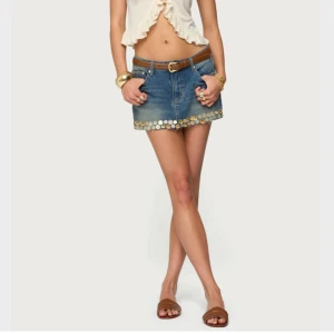 slutsåld Blå jeanskjol med paljetter från Edikted - Slutsåld och supersnygg jeanskjol i blå denim från Edikted, dekorerad med glittriga paljetter längs nederkanten. Kjolen har klassisk femficksdesign, fransig kant och normal passform. Perfekt för dig som vill sticka ut med coola detaljer.