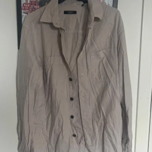 Beige overshirt från Jack & Jones - Stilren beige overshirt från Jack & Jones Premium med svarta knappar och två bröstfickor.  Använd men i mycket bra skick. 