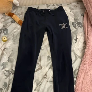 Matinblåa mjukisbyxor med strassdetalj - Svarta mjukisbyxor som är raka till knäna och svänger ut vid knäna På vänster höft finns en strassdetalj med bokstäver. Byxorna har bakfickor och är perfekta för en avslappnad stil.