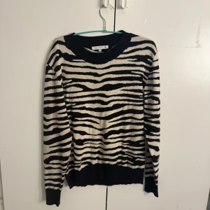 Zebramönstrad stickad tröja från Flash Woman - Säljer en stickad tröja från Flash Woman i storlek XL med svartvitt zebramönster. Tröjan har rund halsringning och långa ärmar, perfekt för dig som vill sticka ut med en djurinspirerad look. Den är i storlek XL men jag har storleken M på tröjor och den sitter som en smäck på mig! 