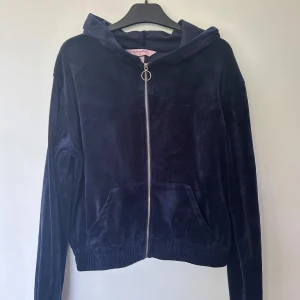 Mörkblå velour hoodie från Hunkemöller - Mysig mörkblå hoodie i velour från Hunkemöller med dragkedja framtill och huva. Jackan har långa ärmar, ribbade muddar och två fickor framtill. Perfekt för en avslappnad och trendig look framför tv:n lika så som en kyligare sommarkväll utomhus. Köptes för 499 kronor på Hunkemöller. Jag har använt den enbart en gång. 