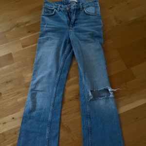 Blå jeans från g perfect jeans med hål på knät - Säljer ett par klassiska blå jeans från g perfect jeans. De har normal passform, bootcut och ett snyggt hål på ena knät för en trendig look. Perfekta till vardags och lätta att matcha med olika toppar.