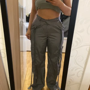 Grå cargopants med knytband - Passar xs och s Säljer ett par grå cargopants med knytband i midjan och längs benen. Byxorna har flera fickor och en loose passform, perfekta för en avslappnad stil.