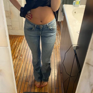 Ljusblå bootcut jeans - Säljer ett par ljusblå jeans med bootcut-modell och låg midja. Jeansen har klassisk femficksdesign och stängs med dragkedja och knapp. Perfekta för en avslappnad och trendig look.