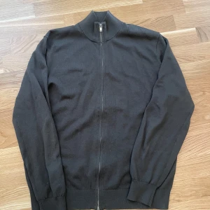 Olivgrön stickad cardigan jacka från Massimo Dutti - Säljer en olivgrön stickad cardigan jacka från Massimo Dutti med dragkedja framtill och ribbade muddar vid ärmslut och krage. Perfekt för lager-på-lager och enkel att matcha med det mesta.