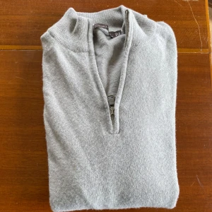 Ljusgrå stickad half zip - Säljer en ljusgrå cashmir tröja från Oscar Jacobson med halv dragkedja framtill och hög krage. Perfekt för lager-på-lager och enkel att matcha med olika outfits.