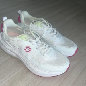 Vita sneakers från Lumberjack - Snygga helt nya vita sneakers från Lumberjack med rosa och limegröna detaljer. Skorna har snörning, mesh-ytor för andning och en tjock, platt sula. Perfekta för en sportig och fräsch look.