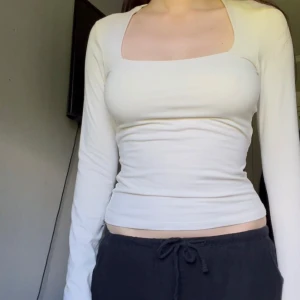 Vit långärmad topp  - Säljer en vit långärmad topp från H&M med tight passform och fyrkantig ringning. Toppen är enkel och stilren, perfekt att matcha med olika outfits. Materialet är mjukt och stretchigt för en bekväm känsla.