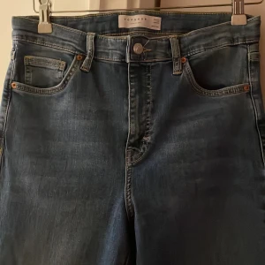Blå flare jeans från Topshop - Säljer ett par blåa jeans från Topshop i modellen Jamie Flare. Byxorna har hög midja, klassisk femficksdesign och utsvängda ben. Perfekta för dig som gillar retrostil och vill ha ett par bekväma och snygga jeans. Väldigt stretchiga och mycket  långa i benen 
