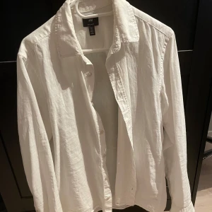 Vit linneskjorta från H&M - Klassisk vit skjorta från H&M i regular fit. Skjortan är tillverkad i linne, har långa ärmar och knäppning framtill. Perfekt för en stilren och avslappnad look. Perfekt skjorta nu till sommaren🍾