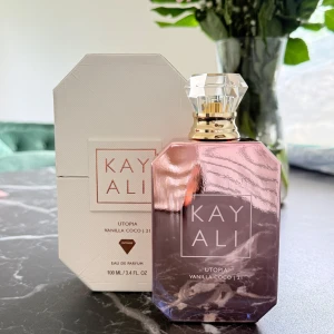 Kayali Utopia Vanilla Coco 21 Eau de Parfum - Kayali Utopia Vanilla Coco 21 är en lyxig parfym i en elegant, multifacetterad glasflaska med guld- och kristalldetaljer. Doften kombinerar krämigt sandelträ, söta vita blommor, mjölkig kokosnöt och vanilj för en drömsk, tropisk känsla. Helt ny endast testad 