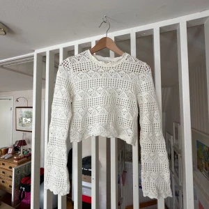 Vit virkad croppad tröja från Monki - Säljer en vit croppad tröja från Monki i storlek XXS. Tröjan är virkad med spetsmönster och har långa ärmar. Perfekt som något att dra över ett linne eller liknande nu i sommar. Använd endast ett fåtal gånger