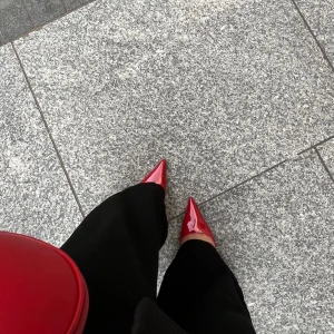 Röda lackade pumps från MNG - Säljer ett par snygga röda pumps från MNG med spetsig tå och smal klack. Skorna har öppen häl med smal rem och är tillverkade i glansigt syntetmaterial. Perfekta för dig som vill sticka ut med färg och stil. Använda en gång 