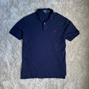 Polo Ralph Lauren pike - En stilren och snygg mörkblå polo ralph lauren pike | Storlek: M Längden från axeln ner till botten är 70cm | Bomull/ t-shirt material