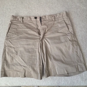 Beige shorts från H&M Regular Fit - Snygga beige shorts från H&M i regular fit-modell. Klassisk design med fickor fram och bak, bälteshällor och knappstängning. Perfekta för varma dagar och enkel att matcha med olika outfits.