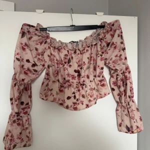 Blommig offshoulder topp från NLY One - Säljer en söt blommig offshoulder topp från NLY One. Toppen har långa puffiga ärmar och en elastisk kant runt axlarna för en bekväm passform. Perfekt för en somrig look! 🌸