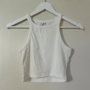 Vit ribbad linnetopp - Säljer en stilren vit ribbad linnetopp. Den är ärmlös och croppad, perfekt för varma dagar. Toppen har en enkel design som gör den lätt att matcha med olika outfits. Perfekt för sommaren! 🌞
