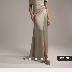 Långklänning - Elegant långklänning med en offshoulder-design och en stilfull slits. Perfekt för speciella tillfällen där du vill glänsa. Klänningen har en smickrande passform och ett vackert fall. Köpt för 1570kr