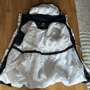 Svart regnjacka från Marine - Säljer en svart regnjacka från Marine Scandinavian Sportswear. Jackan har en praktisk huva och dragkedja framtill. Perfekt för regniga dagar med sin stilrena design och funktionella detaljer.