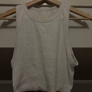 Vit ribbad linnetopp - Säljer en stilren vit ribbad linnetopp. Den är ärmlös och har en rund halsringning. Perfekt för varma dagar eller som ett lager under en jacka.