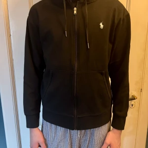 Svart hoodie från Ralph Lauren - Svart Ralph lauren hoodie. Snygg hoodie i storlek M. Säljer pga att jag ej använder den och den är i minsta laget. Personen på bilden är 186 och väger 65kg.