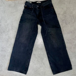 Premium Svarta jeans från Levi's -Unisex - Snygga svarta jeans från Levi's använda en gång. De har en baggy passform och är tillverkade i slitstarkt denim. Perfekta för en stilren look. Snöret är avtagbart. 