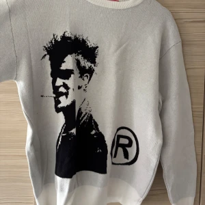 Brad Pitt sweatshirt OANVÄND - Säljer en vit stickad tröja från VIZN FLIM med ett stort svart tryck av Brad Pitt på framsidan. Tröjan är använd typ 1 gång och aldrig tvättat.