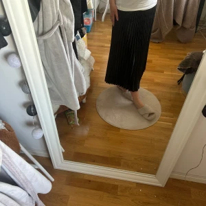 Svart plisserad kjol - Snygg svart plisserad kjol med en elegant och flytande design. Perfekt för att ge en stilren look. Kjolen har en bekväm passform och är lätt att matcha med olika toppar.